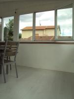 Pavimento in parquet laminato grigio e infissi in PVC bianco per la copertura a veranda del terrazzo.